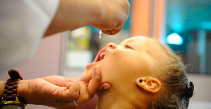 Criança recebendo gotas de vacina infantil
